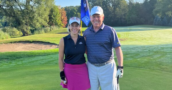 Lauren Trevor and John Simpell smiling together on a golf course